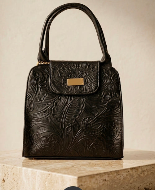Black hand-tooled leather handbag with sunflower floral detailing, gold hardware and dual top handles