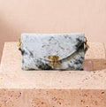 White and black patched cowhide leather clutch with antique brass clasp and shoulder strap