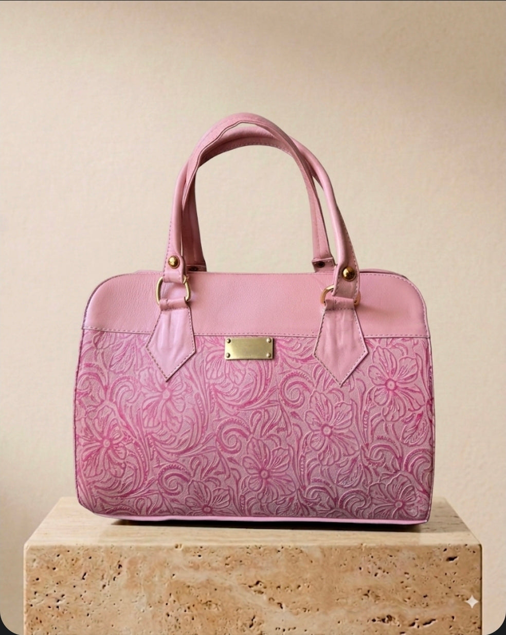 Pink hand-tooled leather barrel handbag with floral scroll detailing and gold hardware